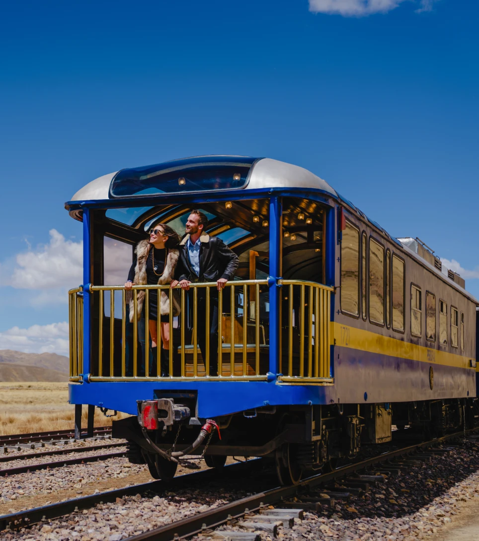 Travelers waving from the Andean Explorer train across the altiplano