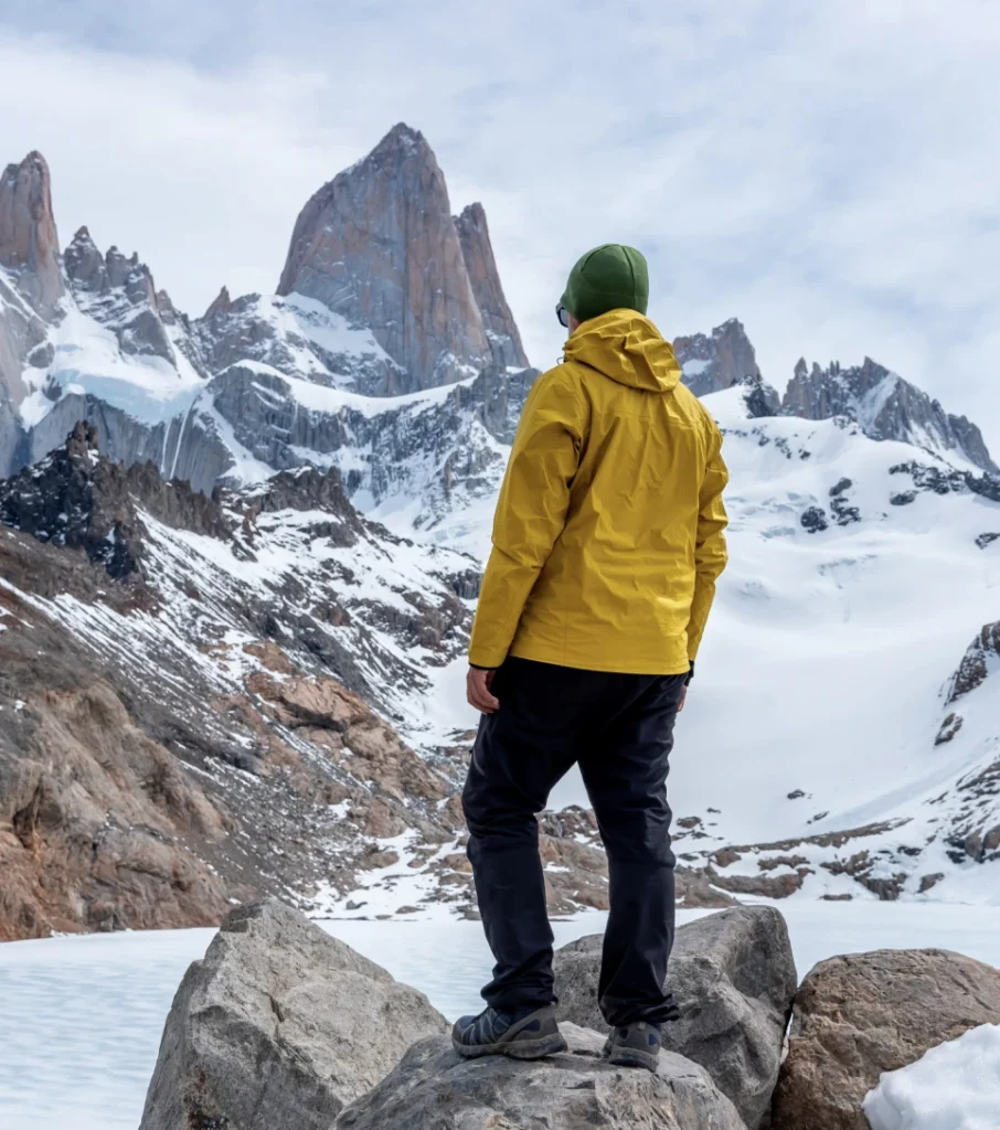 Hiker in yellow jacket facing Cerro Fitz Roy, El Chaltén